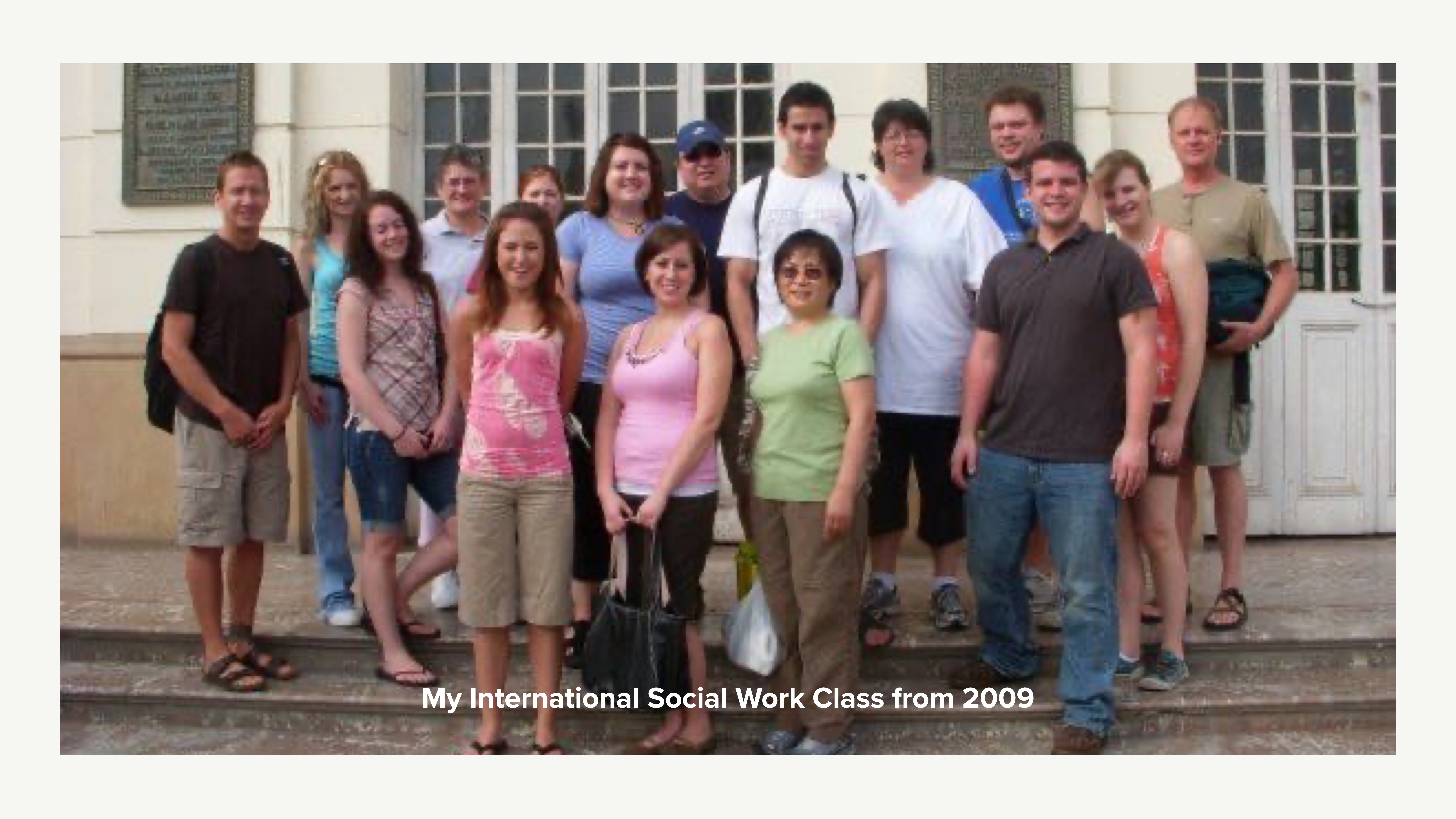 A group of thirteen people stands on stone steps in front of a building with large windows. Text reads: 'My International Social Work Class from 2009.'