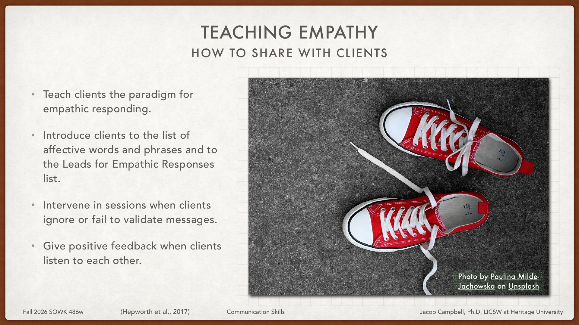 A presentation slide on teaching empathy features four bulleted instructions on the left: teach clients empathic responding paradigms, introduce affective words lists and Leads for Empathic Responses, intervene when clients fail to validate, and give positive feedback for listening. On the right, a photograph displays two red and white high-top sneakers connected by white laces against a dark textured background, suggesting connection and communication as a visual metaphor.