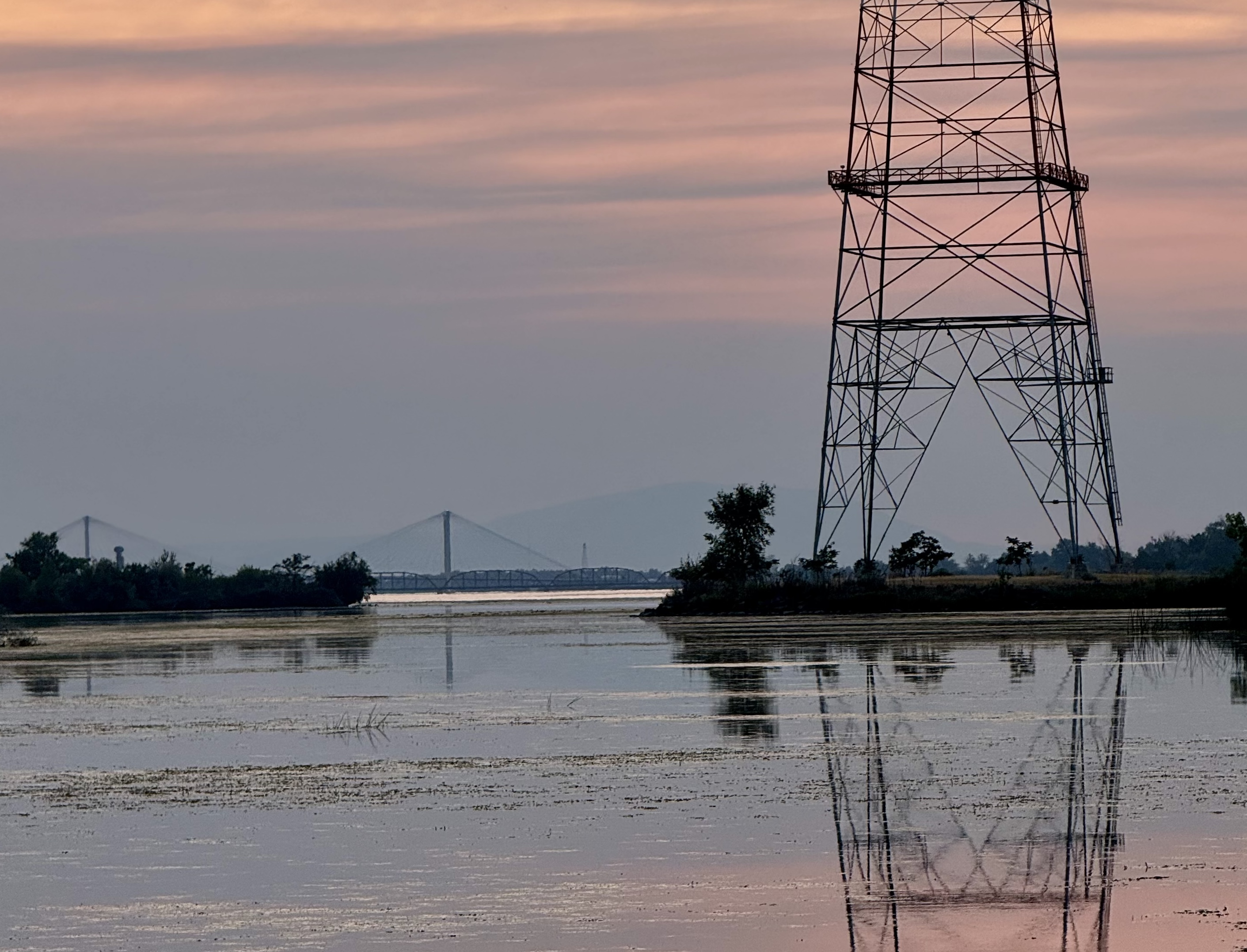 A photo taken by Jacob Campbell of the Columbia River at sunset. Displays a tower and the Blue Bridge in the distance.